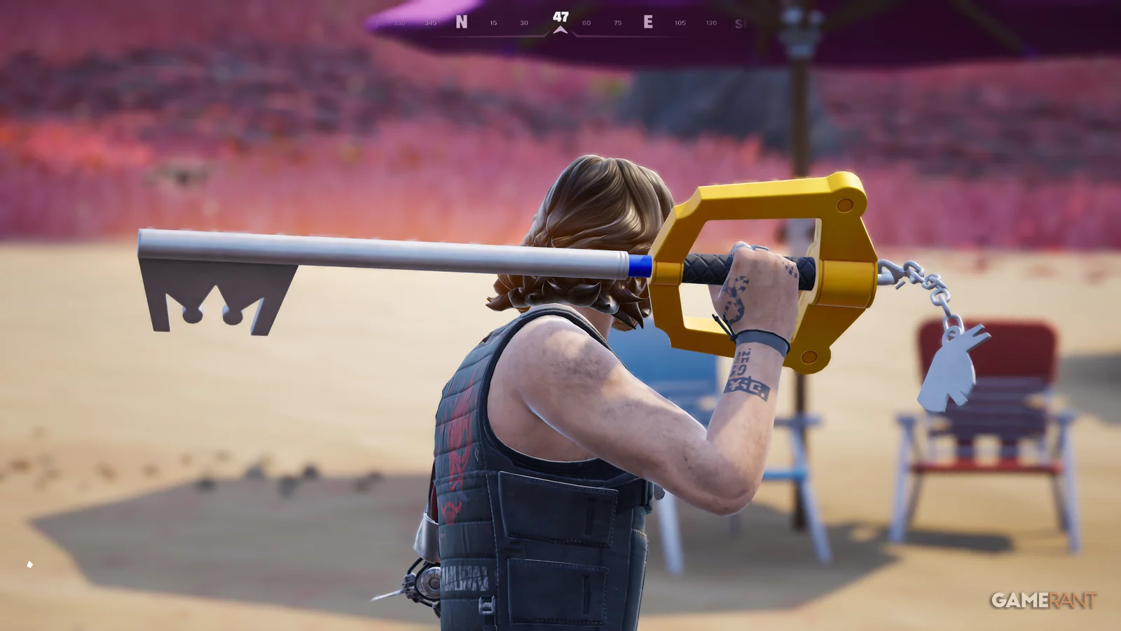 A player holds the Kingdom Key over their shoulder on a beach, the Loot Llama keychain visible on the chain
